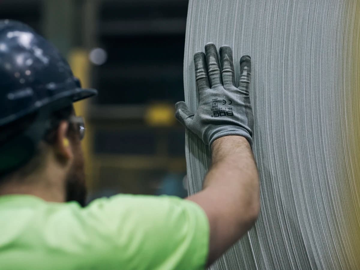 Gloved worker steadying a roll of filter media.