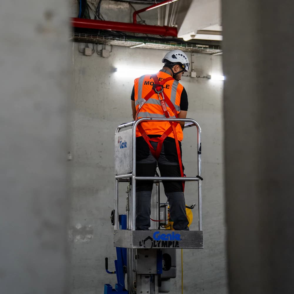 Worker in a hi-vis vest on a lift below ceiling services.